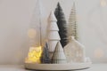 Winter hygge, cozy christmas magical scene, miniature snowy village with lights. Stylish little Christmas trees and house on white