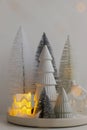 Winter hygge, cozy christmas magical scene, miniature snowy village with lights. Stylish little Christmas trees and house on white