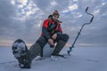 Winter ice fishing. Fisherman on lake catc fish from snowy ice