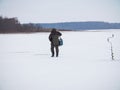 Winter ice fishing, lake, frosty day. fisherman collects gear Royalty Free Stock Photo