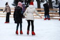 Winter ice rink. The girls in the red skate riding on the ice. Active family sport during the children s  winter holidays Royalty Free Stock Photo