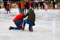 Winter ice rink. A group of People ride fun and fall on the ice. Active family sport during children`s Christmas winter break.