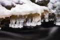 Winter icicles above stream. Frozen water with bubble Royalty Free Stock Photo