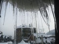 Winter icicles on a window frame with beautiful view of a mountain forest from a ski resort Royalty Free Stock Photo