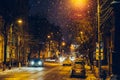 Winter illuminated city street or road with car traffic in snowy weather in night Royalty Free Stock Photo