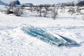 A winter impression - a rowing boat frozen in snow and ice on a lakeshore in Scandinavia