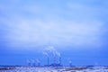 Winter industrial landscape with plants and a large number of smoking pipes. Snowy winter in an industrial city.