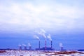 Winter industrial landscape with plants and a large number of smoking pipes. Snowy winter in an industrial city.