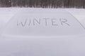 Winter inscription on the glass of a frozen car . Snowfall