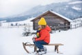 Winter knitted kids clothes. Boy sledding in a snowy forest.