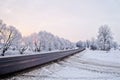 Winter landscape. Asphalted rural road at an early, cold winter sunrise - image