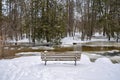 Empty wooden bench, flowing icy cold water and snow on the grounds Royalty Free Stock Photo