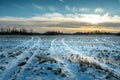 Winter landscape with a farmland and the setting sun behind the clouds Royalty Free Stock Photo