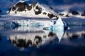 Winter landscape, first sun light on snowcapped mountains, reflections in water, small iceberg, Lemaire Channel near Paradise Bay Royalty Free Stock Photo