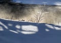 Winter landscape, fog on the river, shadows on the snow, beautiful white snow cover the trees and grass on the river bank Royalty Free Stock Photo