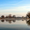 Winter landscape, foggy morning over frozen lake with trees reflecting in mirror water Royalty Free Stock Photo