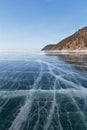 Winter landscape of frozen Baikal Lake with beautiful clear blue ice with lines of cracks and coastal hills Royalty Free Stock Photo