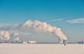 Winter landscape with frozen ice, city and pipes with thick steam
