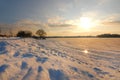 Winter landscape with frozen river covered with snow. Beautiful pink winter sunset illuminates drifts. Eco tourism Royalty Free Stock Photo