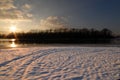 Winter landscape with frozen river covered with snow. Beautiful pink winter sunset illuminates drifts. Eco tourism Royalty Free Stock Photo