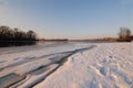 Winter landscape with frozen river covered with snow. Beautiful pink winter sunset illuminates drifts. Eco tourism Royalty Free Stock Photo