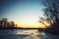 Winter landscape with frozen river, trees, fisherman