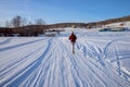 Girl runs along a winter road on a frozen lake towards a village on a hill, on a winter sunny day