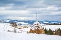 Winter landscape, haystacks on the background of snow-capped mountains and forest