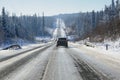 Winter landscape with icy tarmac road on the smooth hills covered with snowy forest in winter