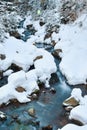 Winter landscape of a mountain river, the water slowly flows down the river bed between snow-covered stones Royalty Free Stock Photo