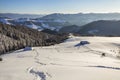 Winter landscape of mountain valley on frosty sunny day. Footprint path in white deep snow leading to small old wooden shepherd