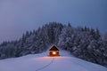 Winter landscape. Mystical night. Old wooden hut on the lawn covered with snow. The lamps light up the house at the evening time. Royalty Free Stock Photo