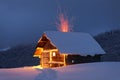 Winter landscape. Mystical night. Old wooden hut on the lawn covered with snow. The lamps light up the house at the evening time. Royalty Free Stock Photo