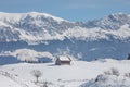 Winter landscape with an old house and Bucegi mountains in the background