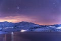 Winter landscape. Panoramic view on the lake and mountains peaks snow-covered at the starry night.