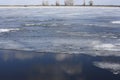 Winter landscape with partly frozen river. Ice floes float on the blue surface. Ice drift. Global warming concept.