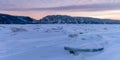 Winter landscape in pink tones with ridged ice on the frozen river at sunset