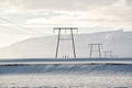 Winter landscape, power lines on a snowy field by the mountains, Iceland Royalty Free Stock Photo