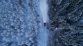 Winter landscape with red car driving at night. Lights of car and winter snowy road in dark forest Royalty Free Stock Photo