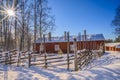 A winter landscape red hut sorrounded by fence and pine trees filled with snow before Christmas with beautiful sunny weather Royalty Free Stock Photo