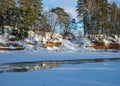 Winter landscape with red sandstone cliffs on the bank of the river Salaca, the sun shines on the trees and the river bank, the Royalty Free Stock Photo