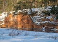 Winter landscape with red sandstone cliffs on the bank of the river Salaca, the sun shines on the trees and the river bank, the Royalty Free Stock Photo