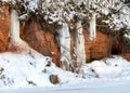 Winter landscape with red sandstone cliffs and icefall on the bank of the river Salaca, the sun shines on the trees and the bank Royalty Free Stock Photo