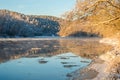 Winter landscape. River view near forest. Snow and frost at sunrise