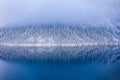 Winter landscape of scenic crystal mountain lake and foggy forested mountain