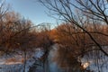 Winter landscape with a small river and bare trees in the foreground. Royalty Free Stock Photo
