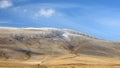 Winter landscape with a smooth hill covered with a yellow dry grass, bare trees and first snow under dark blue sky Royalty Free Stock Photo