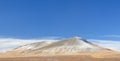 Winter landscape with a smooth hill covered with a yellow dry grass, bare trees and first snow under dark blue sky Royalty Free Stock Photo