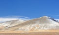 Winter landscape with a smooth hill covered with a yellow dry grass, bare trees and first snow under dark blue sky Royalty Free Stock Photo