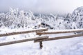 a snow covered fence and a snow covered mountain range with trees in the distance Royalty Free Stock Photo